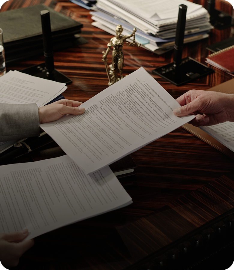 Two people exchanging legal documents at desk.